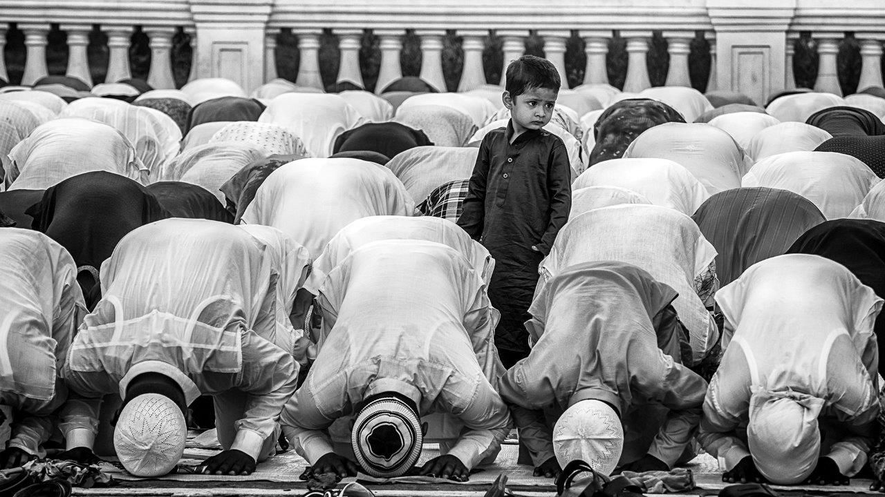 Zdjęcie konkursowe z wystawy pod tytułem Dziecko - Dziecko wśród grupy modlących się ludzi